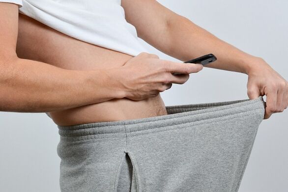 Un home mira un pene agrandado a través dos seus pantalóns